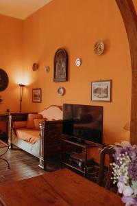 an orange living room with a couch and a television at Casa Caracciolo in Pitigliano