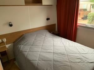 een klein bed in een kamer met een raam bij les sables du midi in Valras-Plage