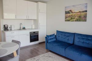 a living room with a blue couch and a kitchen at SeaFly in Palanga