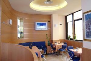een eetkamer met tafels en stoelen en een plafond bij Hotel Nettuno in Sottomarina