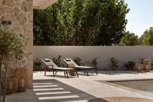 un patio con 2 sedie, un tavolo e una piscina di Onore Villa, Featuring Heated Pool, By ThinkVilla a Gaïtánion