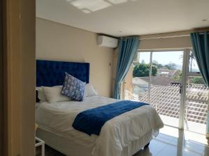 a bedroom with a bed and a balcony at Malusi Bed and Breakfast in Verulam