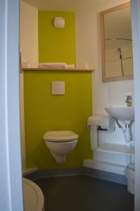 a green bathroom with a toilet and a sink at Premiere Classe Agen in Agen