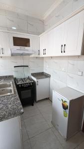 a kitchen with white cabinets and a white refrigerator at Star Max Apartments in Kigali