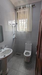 a white bathroom with a toilet and a sink at Star Max Apartments in Kigali