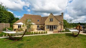 a large house with a yard with two large wooden swings at Warren House and Spa boutique Cotswold stay in Cirencester