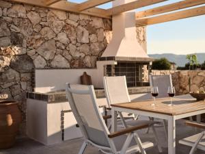 a patio with a fireplace and a table with wine glasses at Onore Villa, Featuring Heated Pool, By ThinkVilla in Gaïtánion