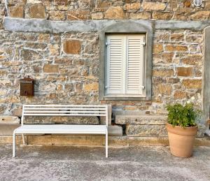 a white bench sitting in front of a stone wall at Kotič na hribu in Dobravlje