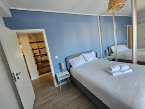 a blue bedroom with a bed with towels on it at Ria Sol Mar Apartment Costa Nova in Costa Nova