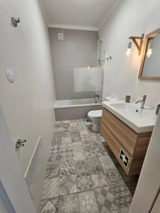 La salle de bains est pourvue d'un lavabo, d'une baignoire et de toilettes. dans l'établissement Ria Sol Mar Apartment Costa Nova, à Costa Nova