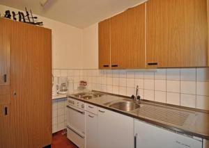 una cocina con electrodomésticos blancos y armarios de madera en Kirschstein Erdgeschoss en Fiesch
