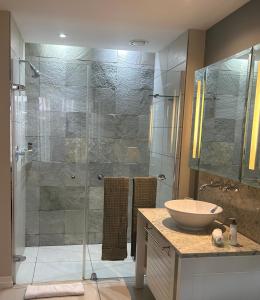 a bathroom with a glass shower with a sink at Eden Island (GIE Apartment) in Eden Island