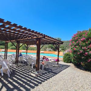 un grupo de mesas y sillas bajo una pérgola cerca de una piscina en Entre mer et montagne, en Le Boulou