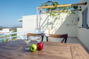 Dois copos e maçãs numa mesa de madeira numa varanda em Solomon Premium House em Kritsa