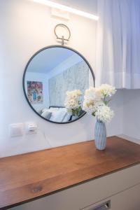 un miroir au-dessus d'une table en bois avec des fleurs dans un vase dans l'établissement Solomon Premium House, à Kritsa