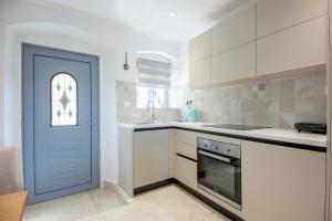 a kitchen with white cabinets and a blue door at Solomon Premium House in Kritsa