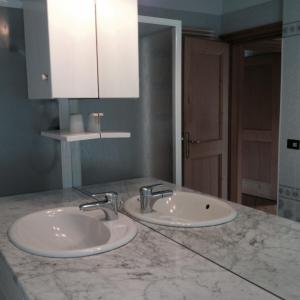 ポッツァ・ディ・ファッサにあるAppartamento Pradelの大理石のカウンターに洗面台2つが付いたバスルーム