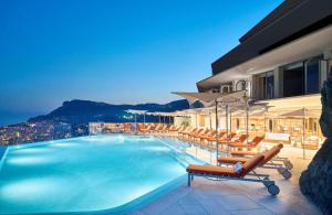 une piscine avec des chaises longues et un bâtiment dans l'établissement The Maybourne Riviera, à Roquebrune-Cap-Martin