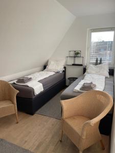 two beds in a room with two chairs and a window at Caros Zimmer Gladbeck in Gladbeck
