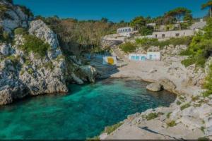 un fiume con acqua blu, rocce e case di Salento_Cala Acquaviva a Marina di Marittima (LE) a Marittima