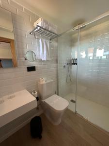 a white bathroom with a toilet and a shower at Hotel El Rosal de Cudillero in Cudillero