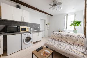 a kitchen with white cabinets and a washer and dryer at Le Cocon Castrais in Castres