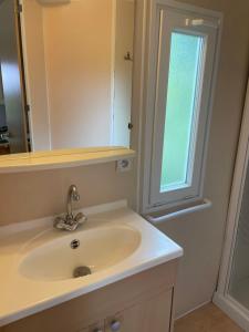 a bathroom with a sink and a mirror and a window at Domaine Camping les Roches in Le Crestet