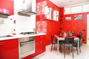 una cucina con armadi rossi e un tavolo con sedie di Metro Solfatara Apartment by Wonderful Italy a Pozzuoli