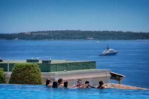 a group of people in a swimming pool with a cruise ship at Moha - Piscine - Tennis - Parking - VCA in Cannes