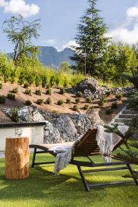 a wooden bench sitting in the grass with a tree stump at Villa T Apartments & SPA in Zakopane