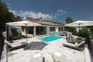 een villa met een zwembad en 2 parasols bij Casa Maya Deluxe Appartment with a pool in Opatija
