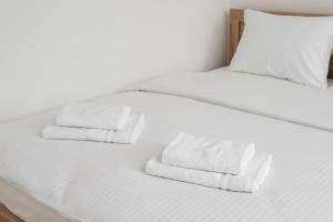 Una cama blanca con dos toallas plegables. en Żoliborz Comfort Studio, en Varsovia