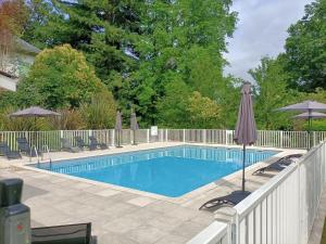 a swimming pool with a fence and an umbrella at Résidence de la Source by Euclenima in Salies-de-Béarn
