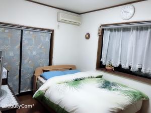um quarto com uma cama e uma janela com um relógio em friendly 民宿 em Sagamihara