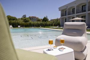 a patio with a chair and two glasses of wine at Hotel H4 Cangas 3 Superior in Cangas de Morrazo