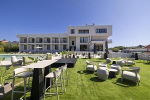 a building with a lawn with tables and chairs at Hotel H4 Cangas 3 Superior in Cangas de Morrazo