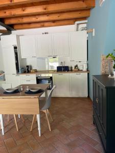 eine Küche mit weißen Schränken sowie einem Tisch und Stühlen in der Unterkunft Ari’sNest in Caprino Veronese