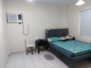a bedroom with a bed and a fan and a chair at Prem Home Stay in Sharjah
