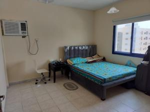 a bedroom with a bed and a desk and a window at Prem Home Stay in Sharjah