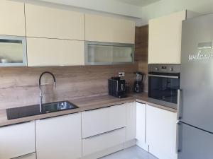 uma cozinha com armários brancos, um lavatório e um frigorífico em Apartments Mare em Banjol