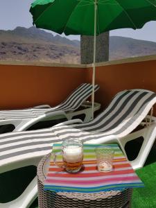 a table with a green umbrella and two chairs at THE HAPPINESS PENTHOUSE Dream Holiday at 100m Beach in Candelaria