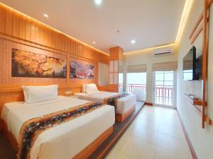 a hotel room with two beds and a flat screen tv at Little Tokyo in Yogyakarta