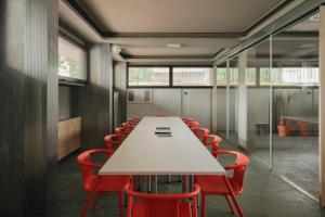 a conference room with a white table and red chairs at 'RE-Dama Hostel in Florence