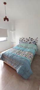 uma cama num quarto branco com um edredão azul em EL CARMEL em Paraná