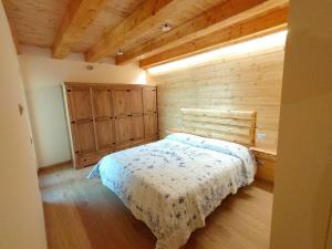 1 dormitorio con 1 cama y pared de madera en Bella Italia chalet, en Massino Visconti