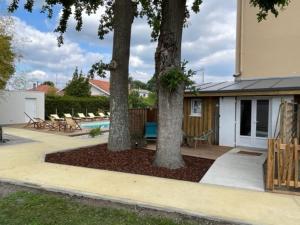 a patio with three trees and a pool at Hôtel Le Grain de Sable in Arès