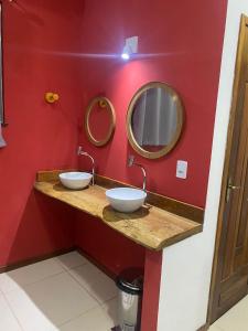 uma casa de banho com 2 lavatórios e uma parede vermelha em Hostel Flor de Ipê em Barreirinhas