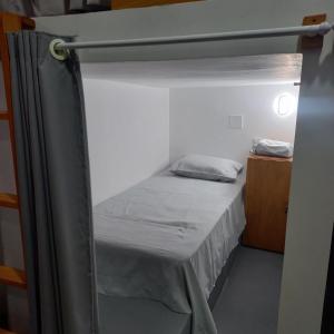 Hostel Flor de Ipê في باريرينهاس: سرير بطابقين في غرفة صغيرة مع ستارة
