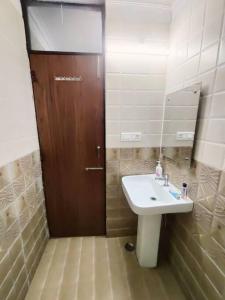 bagno con lavandino e porta in legno di RJ Homestay a Dehradun