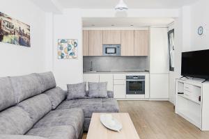 a living room with a gray couch and a kitchen at Nautilus 3 - Elegante Apartamento para 6 con Piscina, Wifi y AC en Rota in Rota
